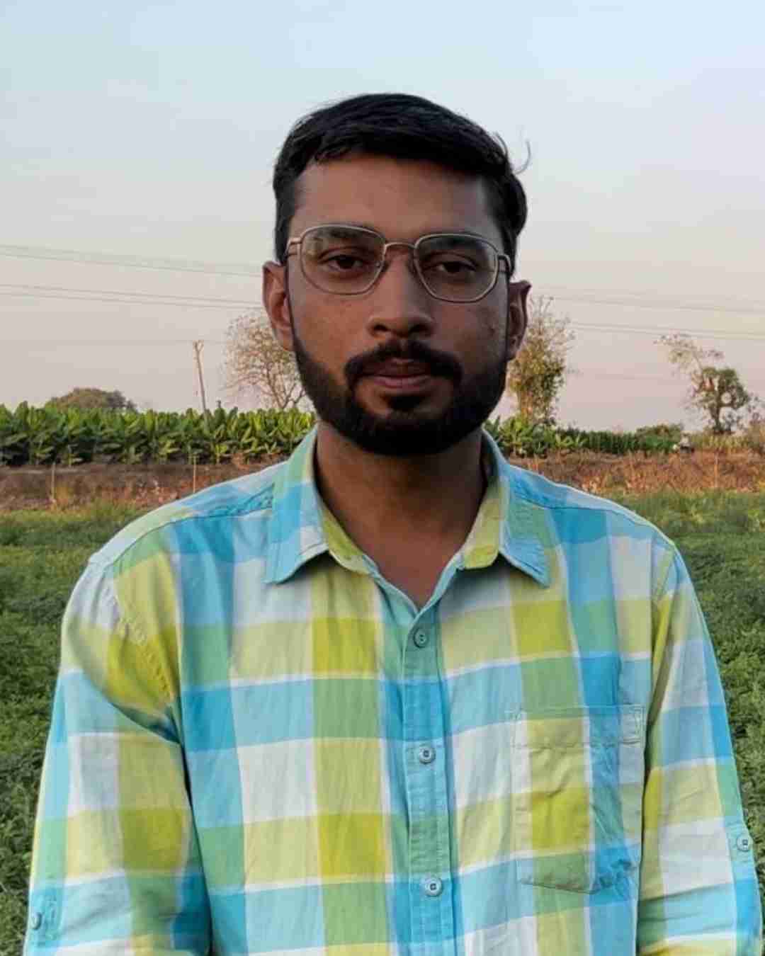 A vegetable grower holding fresh capsicums in a polyhouse in Pune.